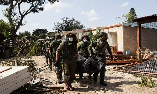 Mortal remains of residents & militants lie in the grounds of ravaged Israeli kibbutz