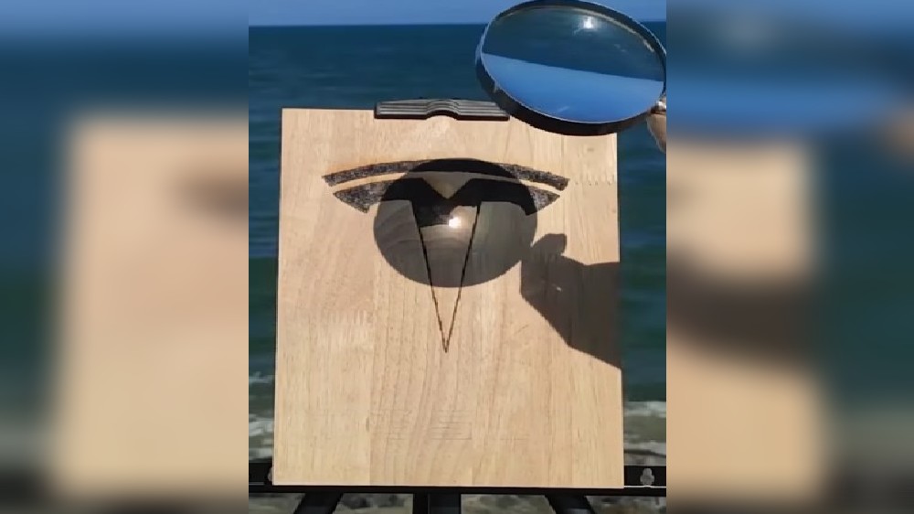 Man draws Teslas symbol extraordinary through magnifying glass Man draws Teslas symbol extraordinary through magnifying glass