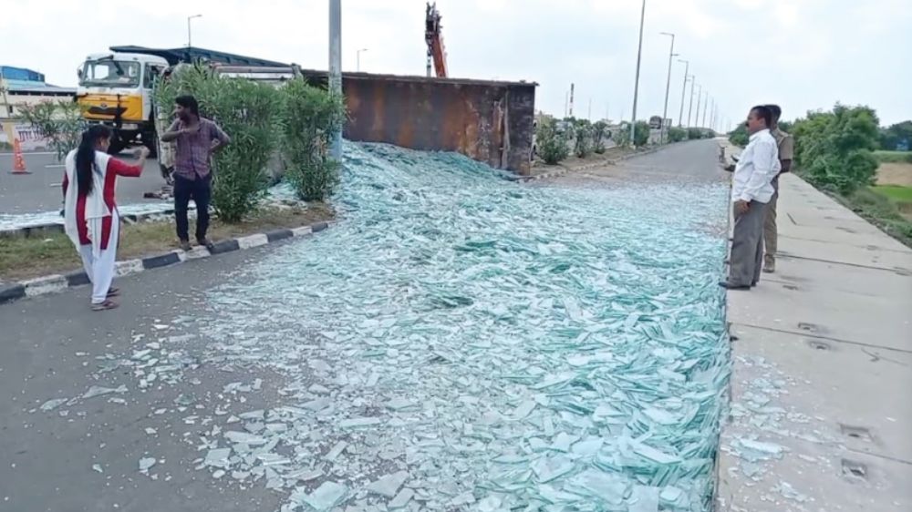 Truck carrying tonnes of glass flips on service road, blocks traffic