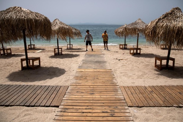 Greeks return to beaches in heatwave, but keep umbrellas apart